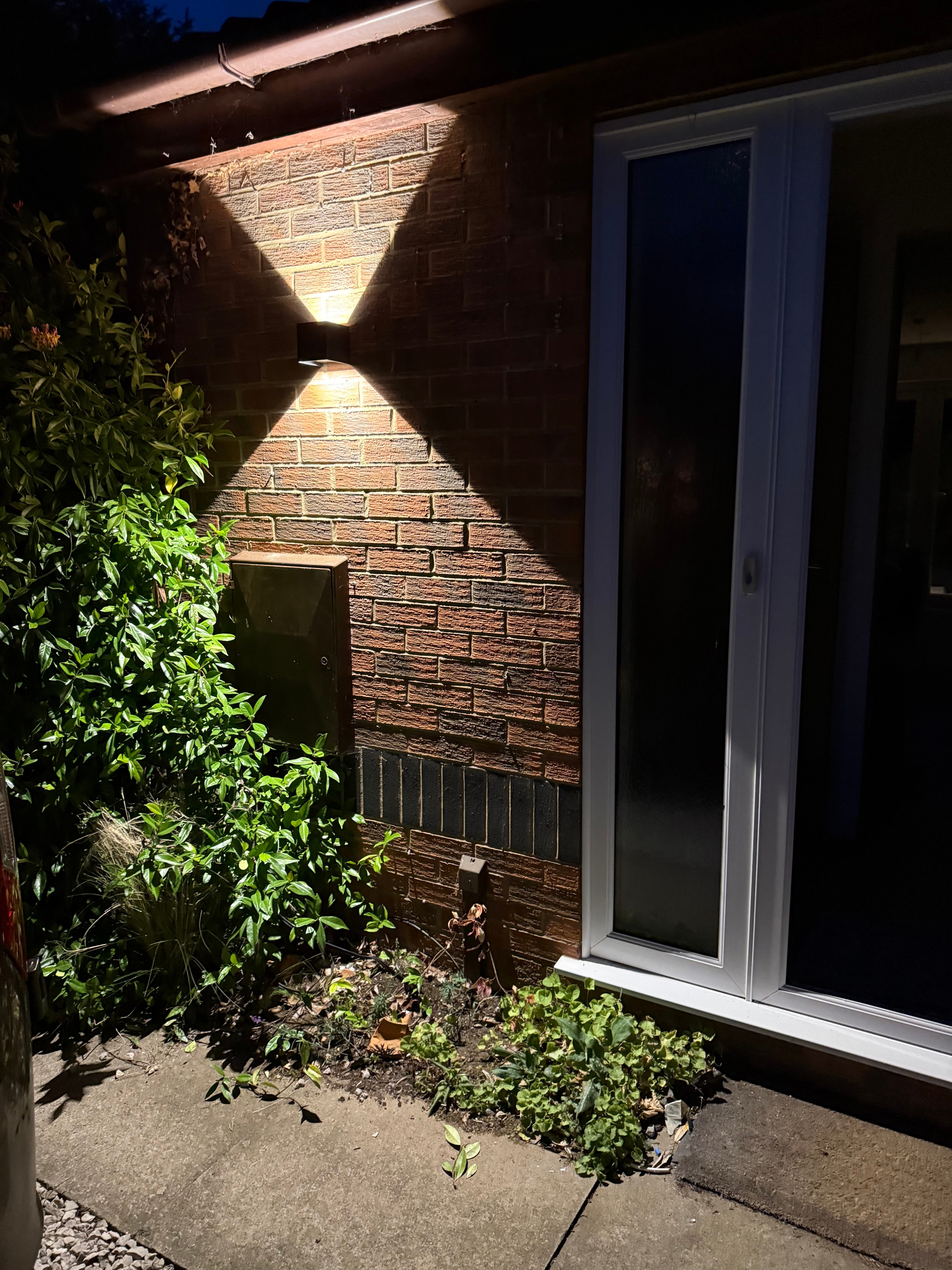 Exterior wall light illuminating brick facade at night
