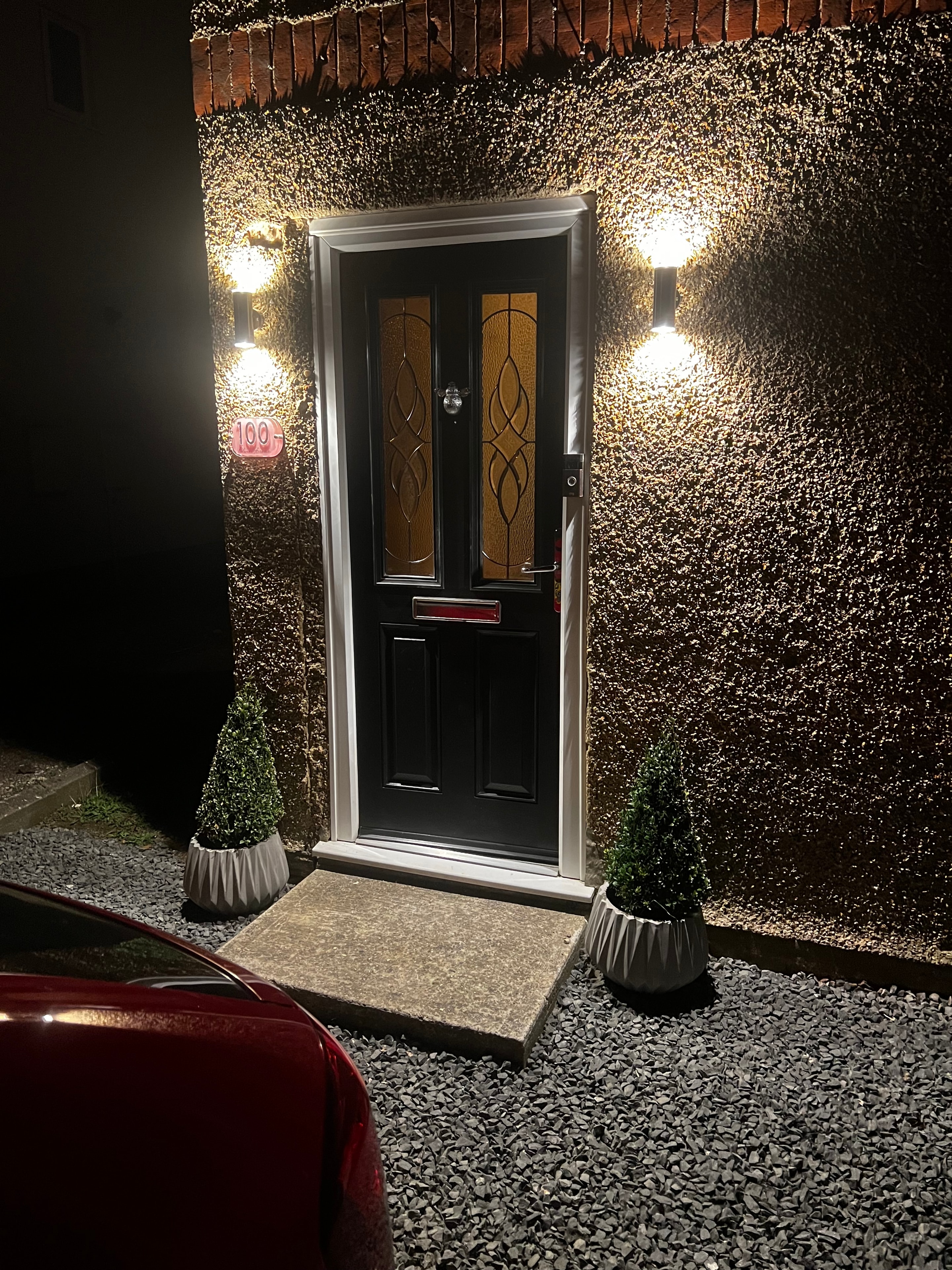 Front door with wall lights illuminating brick at night
