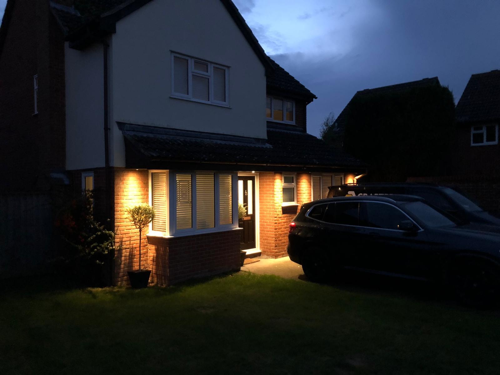 House exterior with warm uplights at dusk